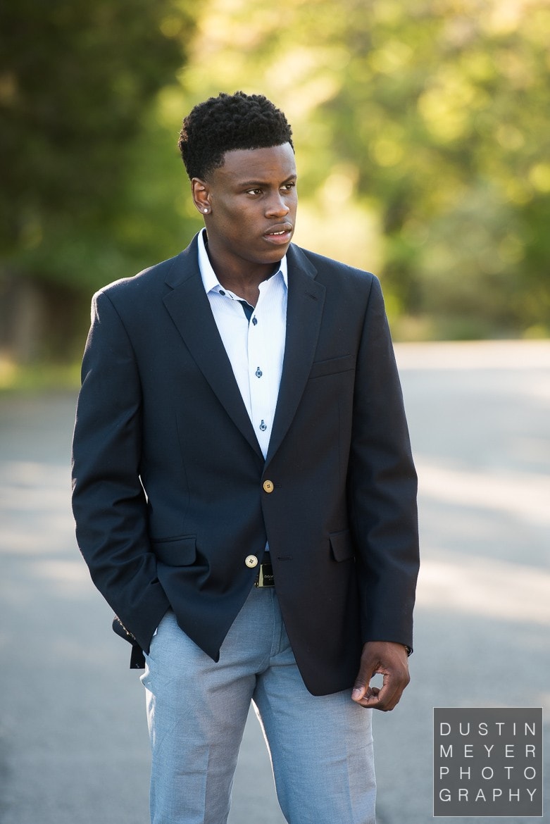 a black male model wearing jeans and a suit jacket outdoors